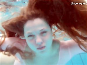 red-haired Simonna showcasing her figure underwater